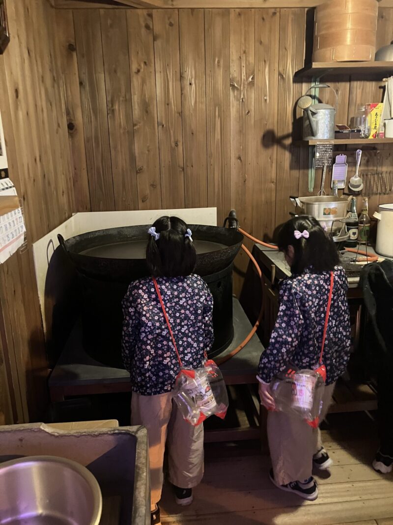 安藤百福さんの研究小屋にある大きい鍋を見ている二入の子供